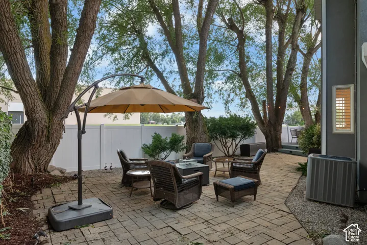 Expansive paver patio with mature trees providing natural shade