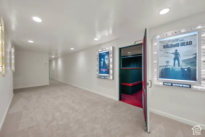 Recessed lighting illuminates the carpeted hallway and adjoining theater room entrance