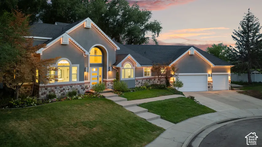 Stucco exterior with stone accents, arched windows, an arched entry, a concrete driveway, and a two-car garage
