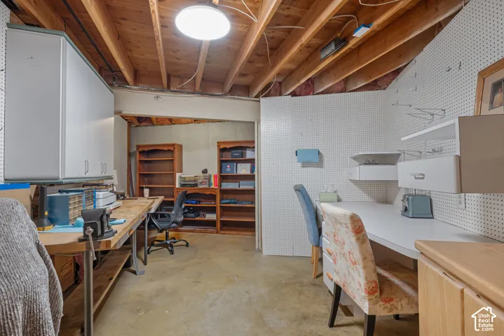 Exposed ceiling joists, concrete flooring, built-in pegboard wall, built-in shelving, and built-in cabinetry