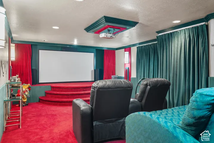 Dedicated media room with a projection screen, raised stage, and permanent wall-mounted projector