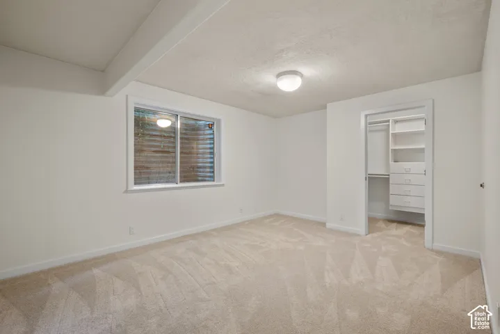 Carpeted room with a window, recessed lighting, and a closet with built-in shelving and drawers