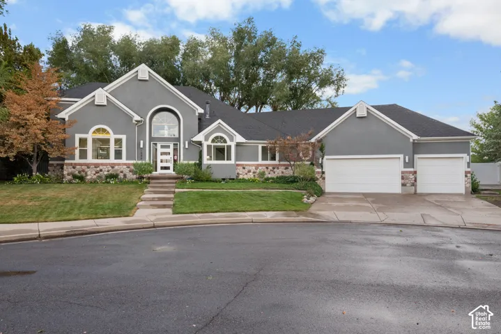 Stucco exterior with stone accent detailing, arched windows, covered entrance, and an attached two-car garage