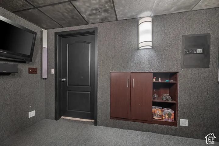 Integrated wall cabinetry with open shelving, recessed electrical panel, wall-mounted sconce, and textured wall coverings