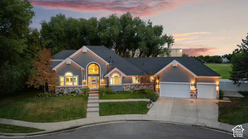 Stucco exterior with stone accents, arched windows, an arched entry, a concrete driveway, and attached garage doors