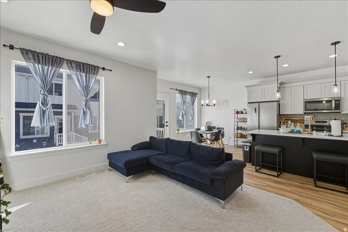 Open concept living area featuring a ceiling fan, recessed lighting, and a large window