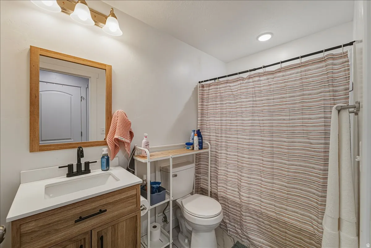 Bathroom featuring a wood-finish vanity with a white countertop and integrated sink, a large wood-framed mirror, and a matte black single-handle faucet