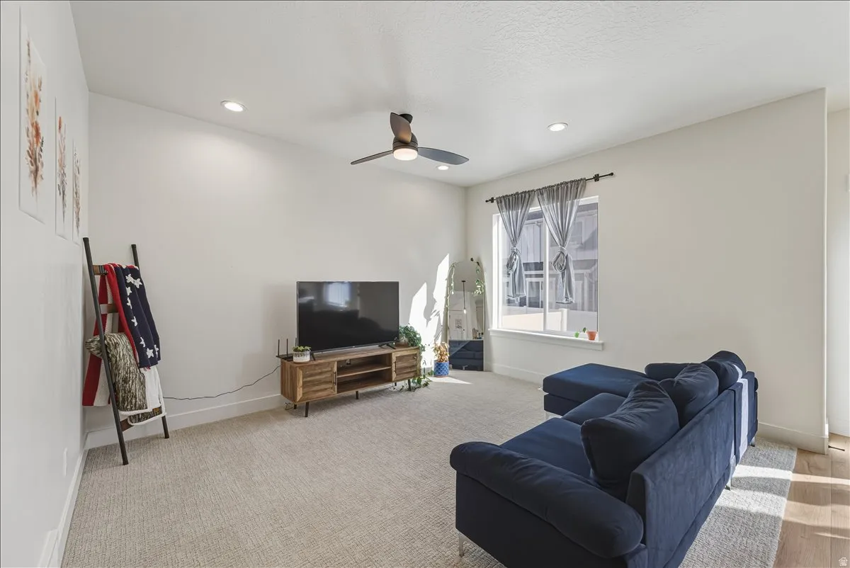 Carpeted flooring, recessed lighting, ceiling fan, and a large window with privacy blinds