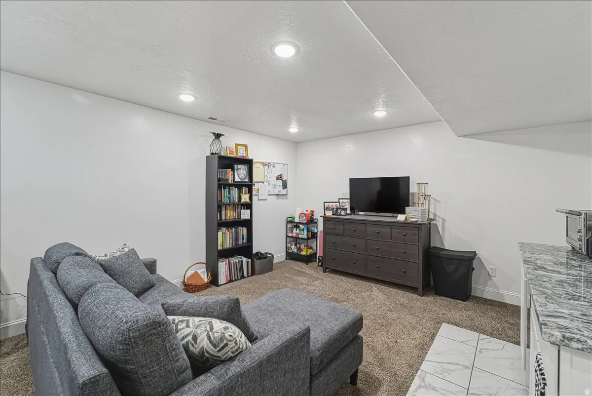 Recessed lighting, carpeted flooring, white walls, built-in shelving, and a tiled counter surface