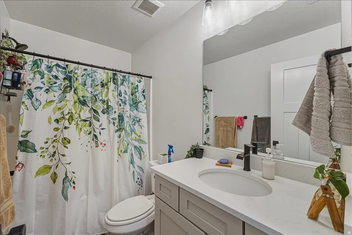 Neutral color palette with white walls, a vanity featuring a light gray cabinet, a white countertop with an integrated oval sink, and a black wall-mounted faucet