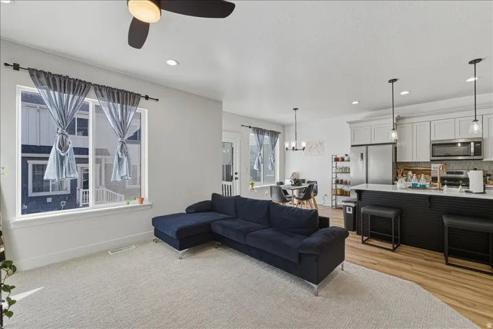 Open concept living area featuring a ceiling fan, recessed lighting, and a large window
