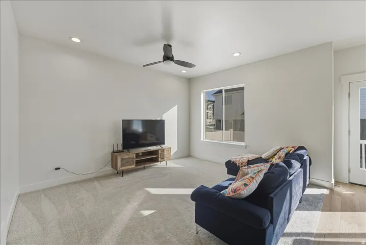 Recessed lighting, ceiling fan, multiple windows, light-colored carpeting, and light wood-finish flooring
