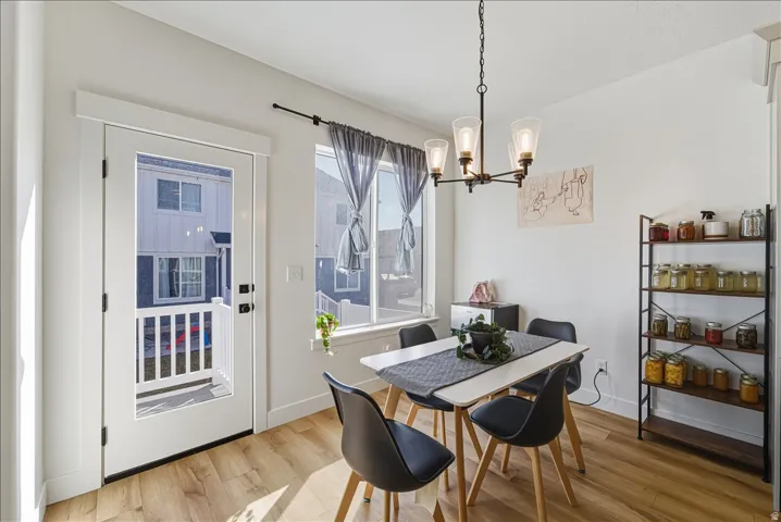 Recessed lighting, wood-finish flooring, white walls, black chandelier, and a white framed window
