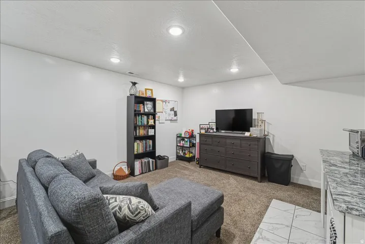 Recessed lighting, carpeted flooring, white walls, built-in shelving, and a tiled counter surface