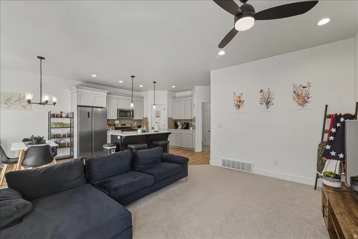 Open-concept layout featuring a kitchen with light-colored cabinetry, stainless steel appliances, and an island with counter seating