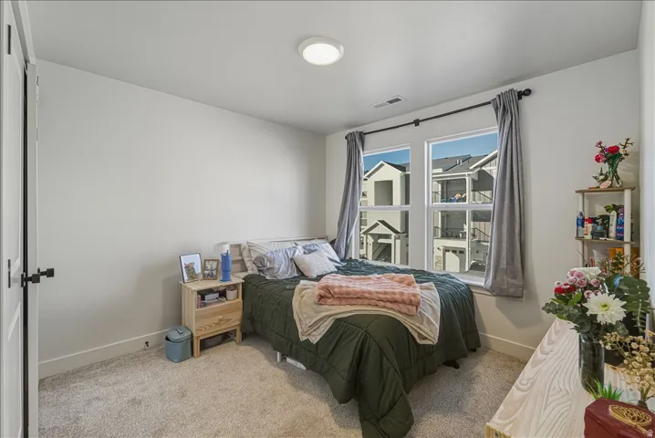 Recessed lighting, light-toned carpeting, and multiple windows with dark curtain rods