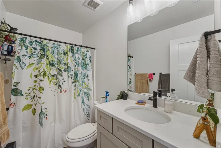 Neutral color palette with white walls, a vanity featuring a light gray cabinet, a white countertop with an integrated oval sink, and a black wall-mounted faucet