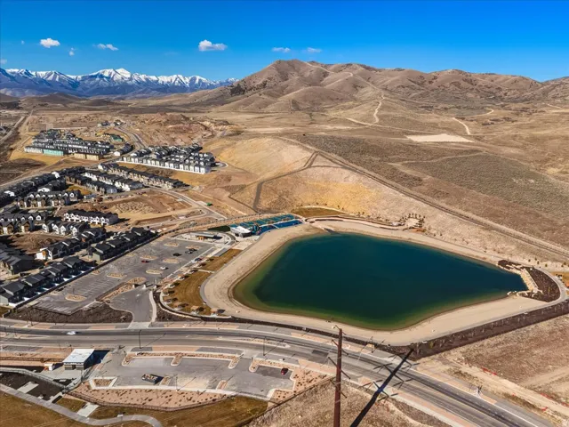 Expansive residential community featuring a prominent water feature, surrounded by paved roadways and natural landscaping, with distant snow-capped mountains