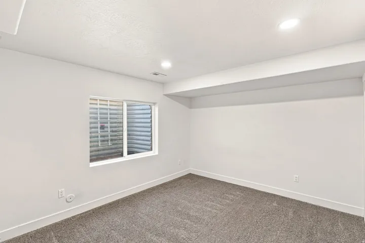 Recessed lighting, wall-to-wall carpeting, egress window, white trim, and light-toned walls