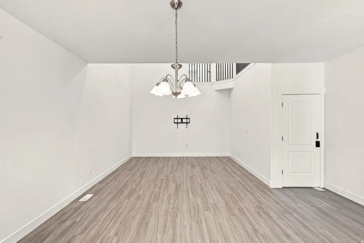 Open-concept space featuring high ceilings, wood-finish flooring, a contemporary chandelier, and a white paneled door