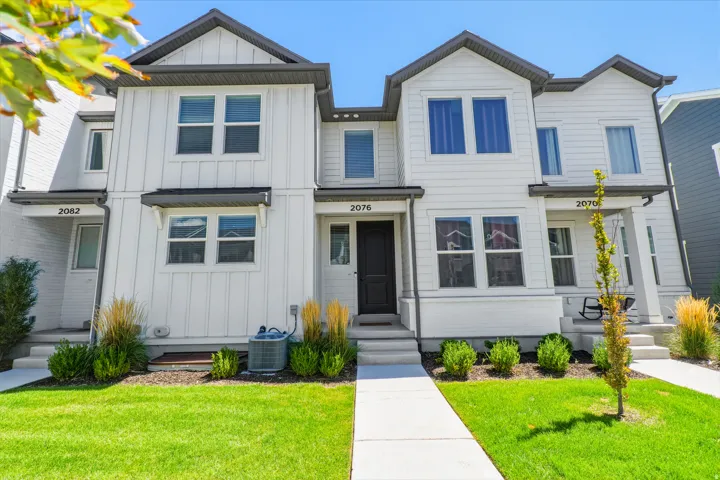 White exterior siding with dark trim accents, gabled rooflines, and a well-maintained lawn