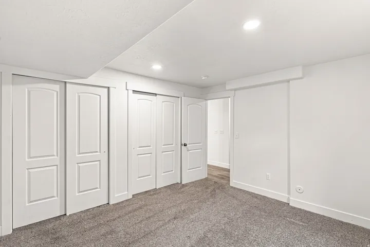 Wall-to-wall carpeting, multiple sliding closet doors, and recessed ceiling lighting