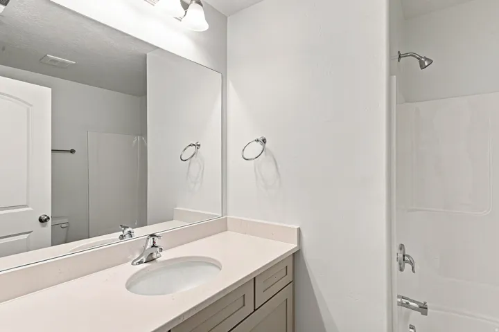 Integrated vanity with an undermount sink, a chrome faucet, and a large wall mirror