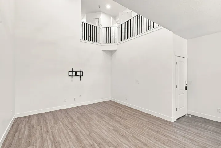 High ceilings, wood-finish flooring, two-story living space, open-concept design, upper-level railing