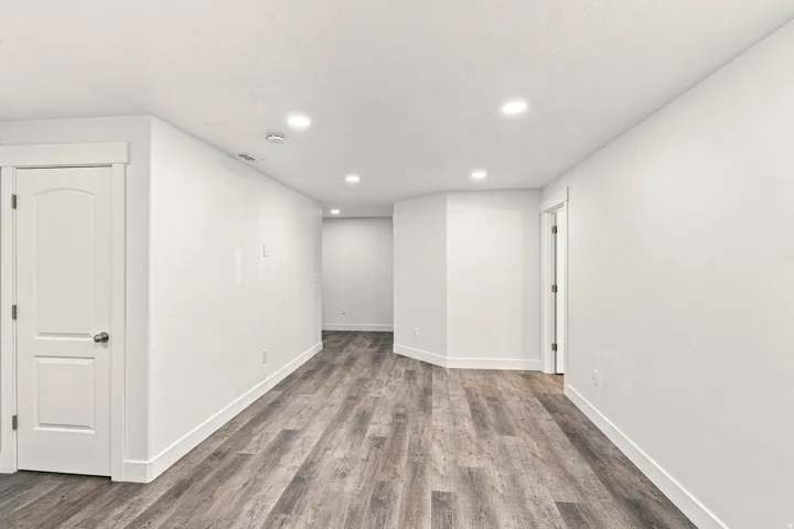 Recessed lighting illuminating the room, wood-finish flooring, white walls, and white trim