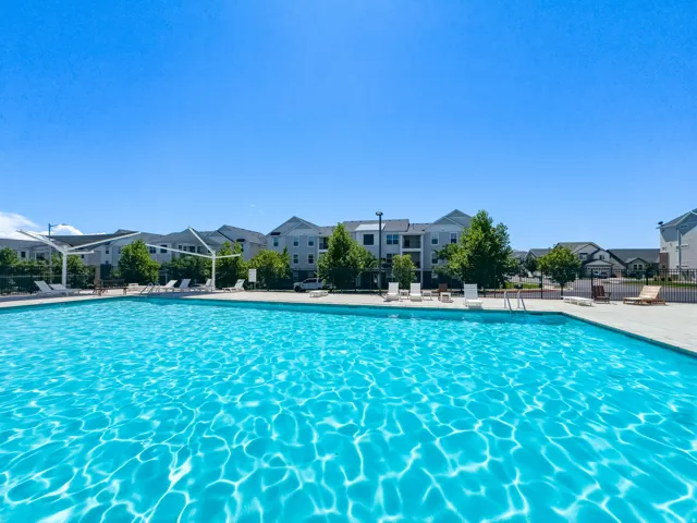 Resort-style pool with a spacious deck, surrounded by residential buildings and mature trees