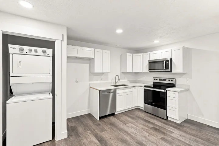Kitchen featuring white cabinetry, stainless steel appliances, light countertops, and wood-finish flooring