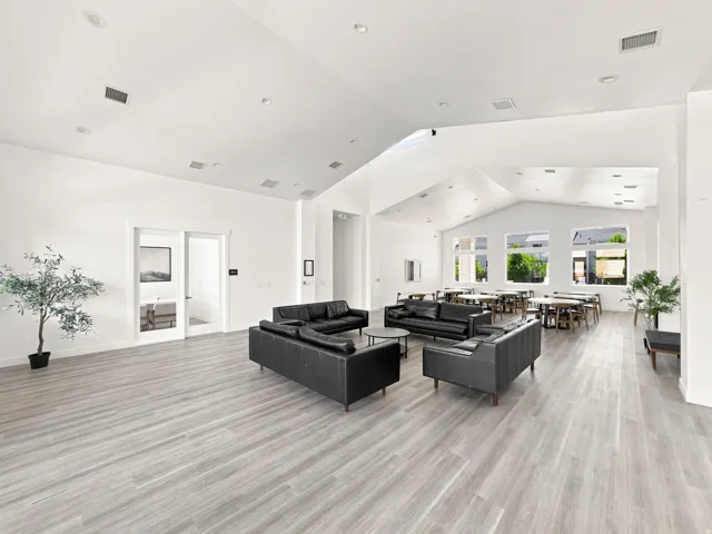 Spacious room featuring vaulted ceilings, recessed lighting, wood-finish flooring, and multiple windows