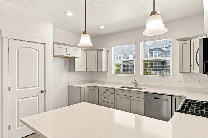 Kitchen featuring a central island, light gray cabinetry, stainless steel appliances, and pendant lighting