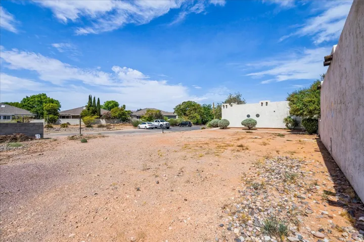 Expansive land parcel featuring existing perimeter wall, mature landscaping, and clear sky