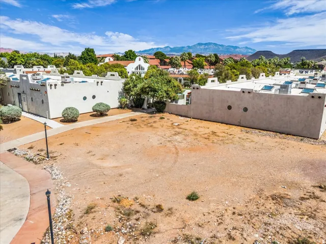 Undeveloped lot with desert landscaping, surrounded by pueblo-style architecture