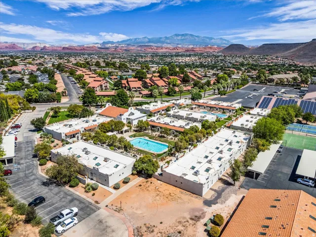 Expansive community with multiple buildings, two outdoor swimming pools, two tennis courts, and large solar panel arrays