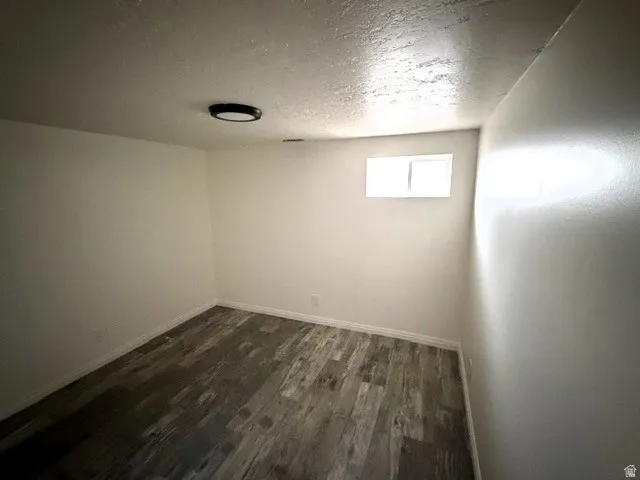Wood-finish flooring, white walls, and a flush-mount ceiling light fixture