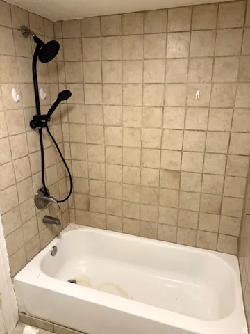 Bathtub with a tiled surround and a black finish shower fixture