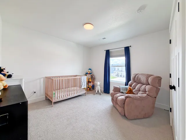 Carpeted flooring, white walls, flush mount ceiling light, window with blinds, and a white paneled door with black hardware