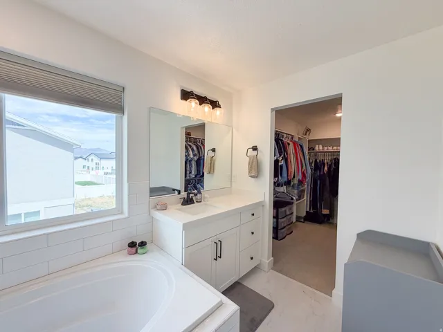 Primary Bathroom with Dual Vanity and Walk-In ClosetThis spa-inspired bathroom features a double-sink vanity with white cabinetry, quartz countertops, and polished chrome fixtures