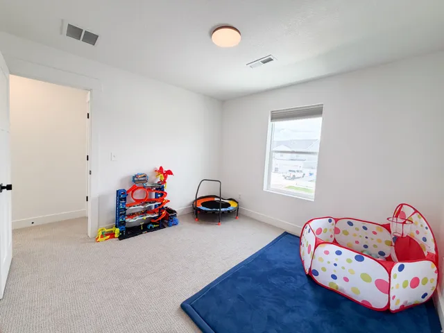 Carpeted room featuring a single window, white walls, and a flush-mount ceiling light