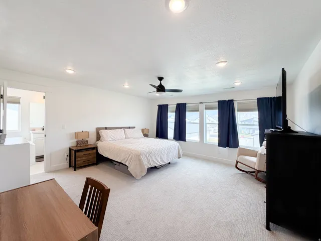 Spacious room with white walls, carpeted flooring, and a ceiling fan