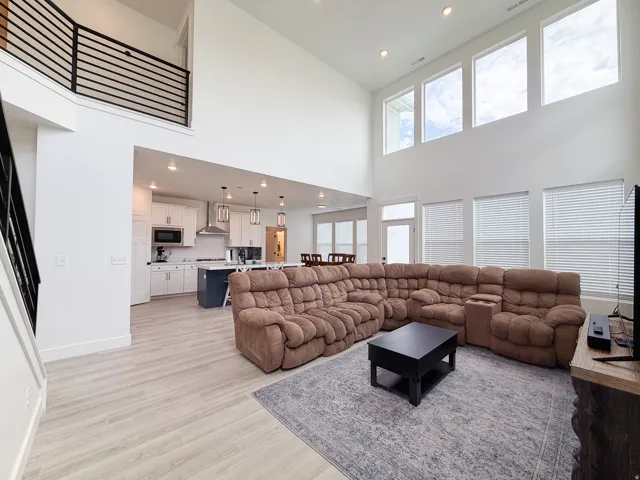 High ceilings, abundant natural light from tall windows, open-concept design, wood-finish flooring, and a modern kitchen with white cabinetry