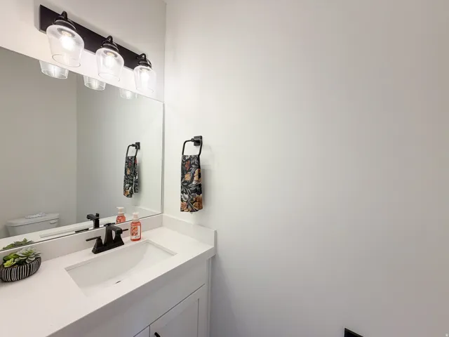 Vanity with integrated sink, stone-finish countertop, dark-finish faucet, and coordinating wall-mounted light fixture