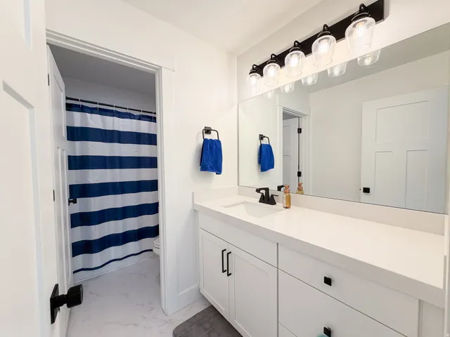 White vanity with ample counter space, undermount sink, and black fixtures