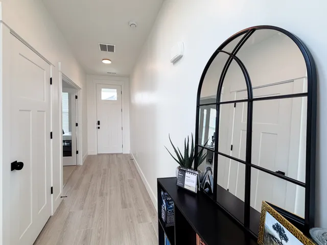 White interior doors with black hardware, wood-finish flooring, recessed ceiling lighting, and a front entry door with an integrated window
