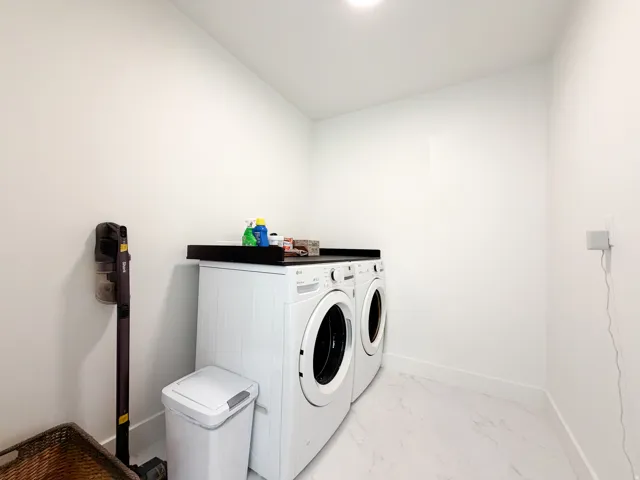 Laundry area featuring white walls, marble-finish flooring, a white washing machine, and a white dryer