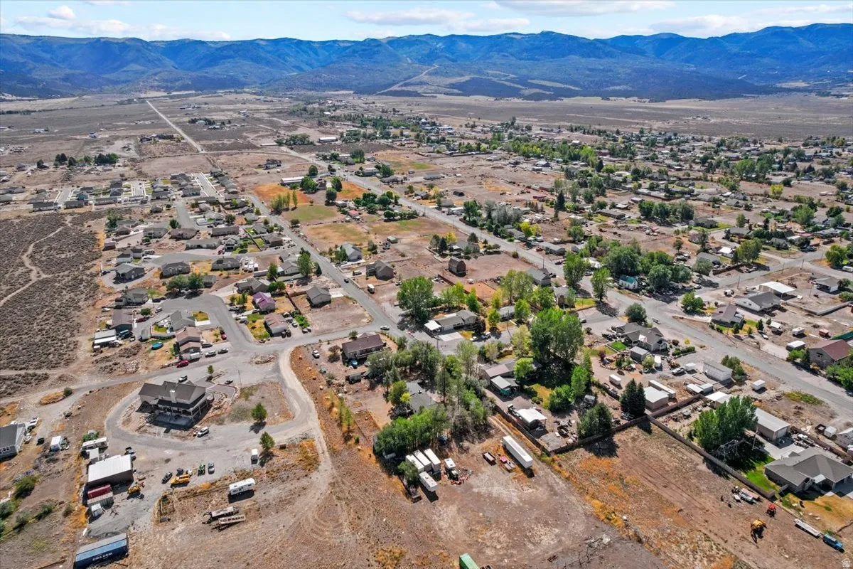 Aerial perspective showcasing scattered residential properties, mature trees, and mountainous terrain in the background