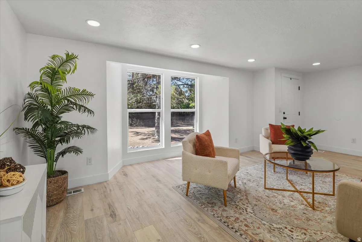 Recessed lighting, light wood-finish flooring, white walls, and a white paneled door