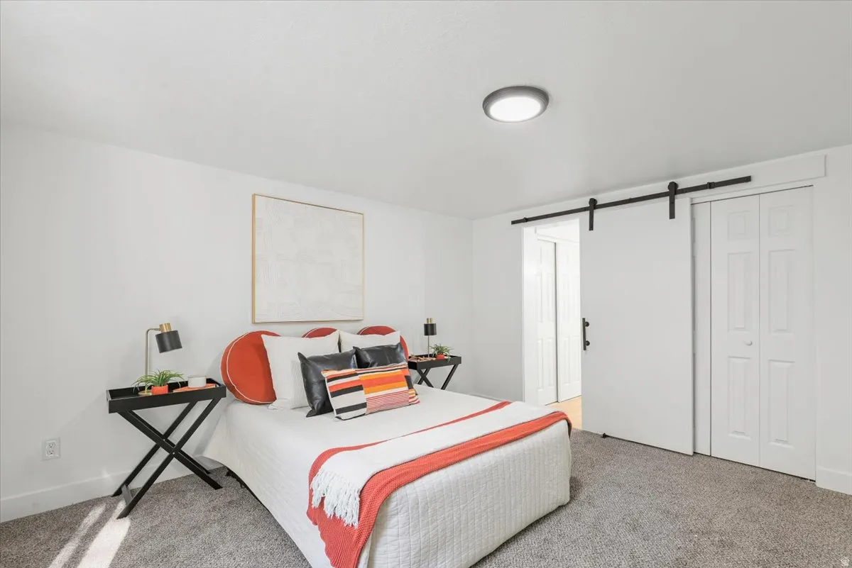 Recessed ceiling lighting, barn door entry, bi-fold closet doors, and light gray carpeting